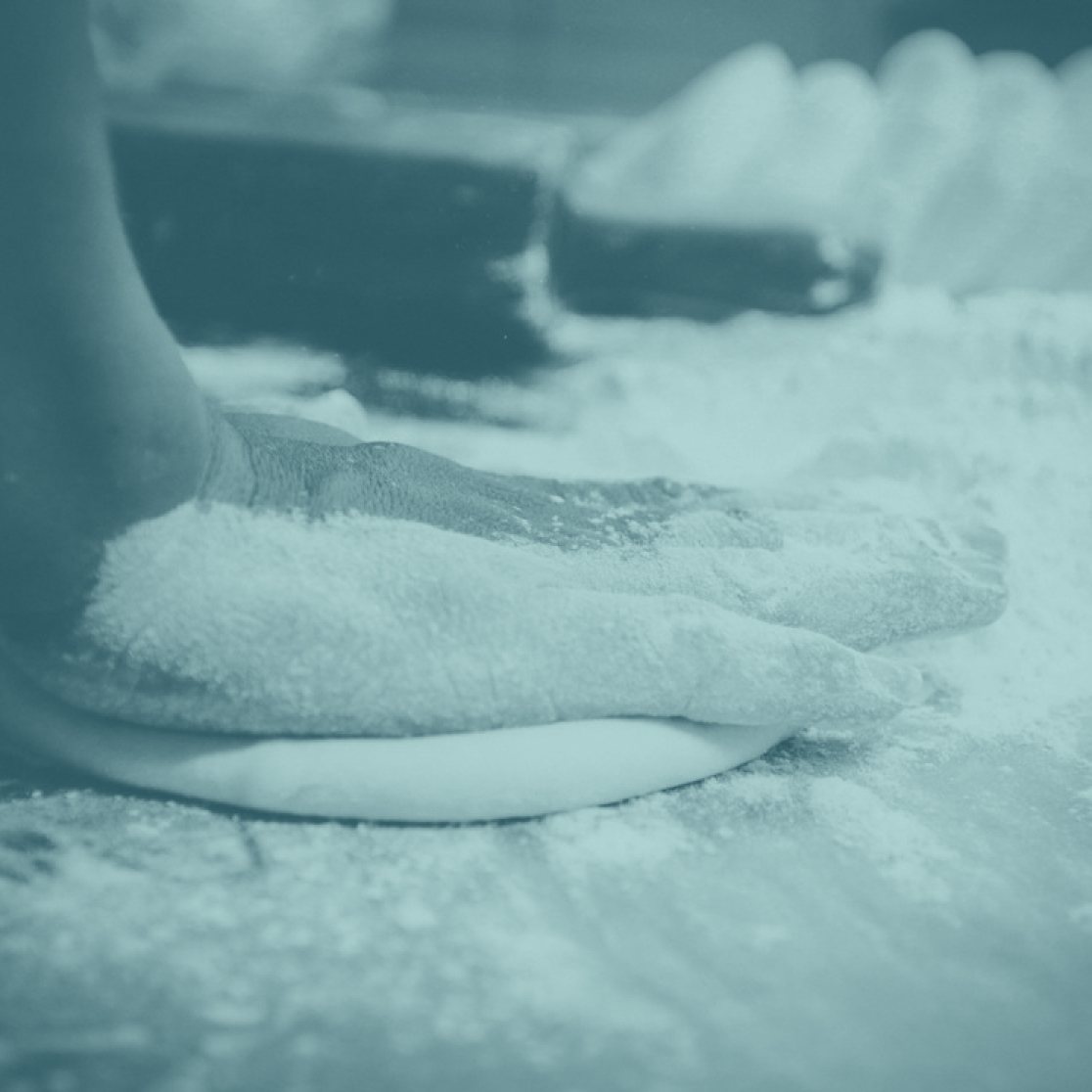 Hands pressing dough on a floured table