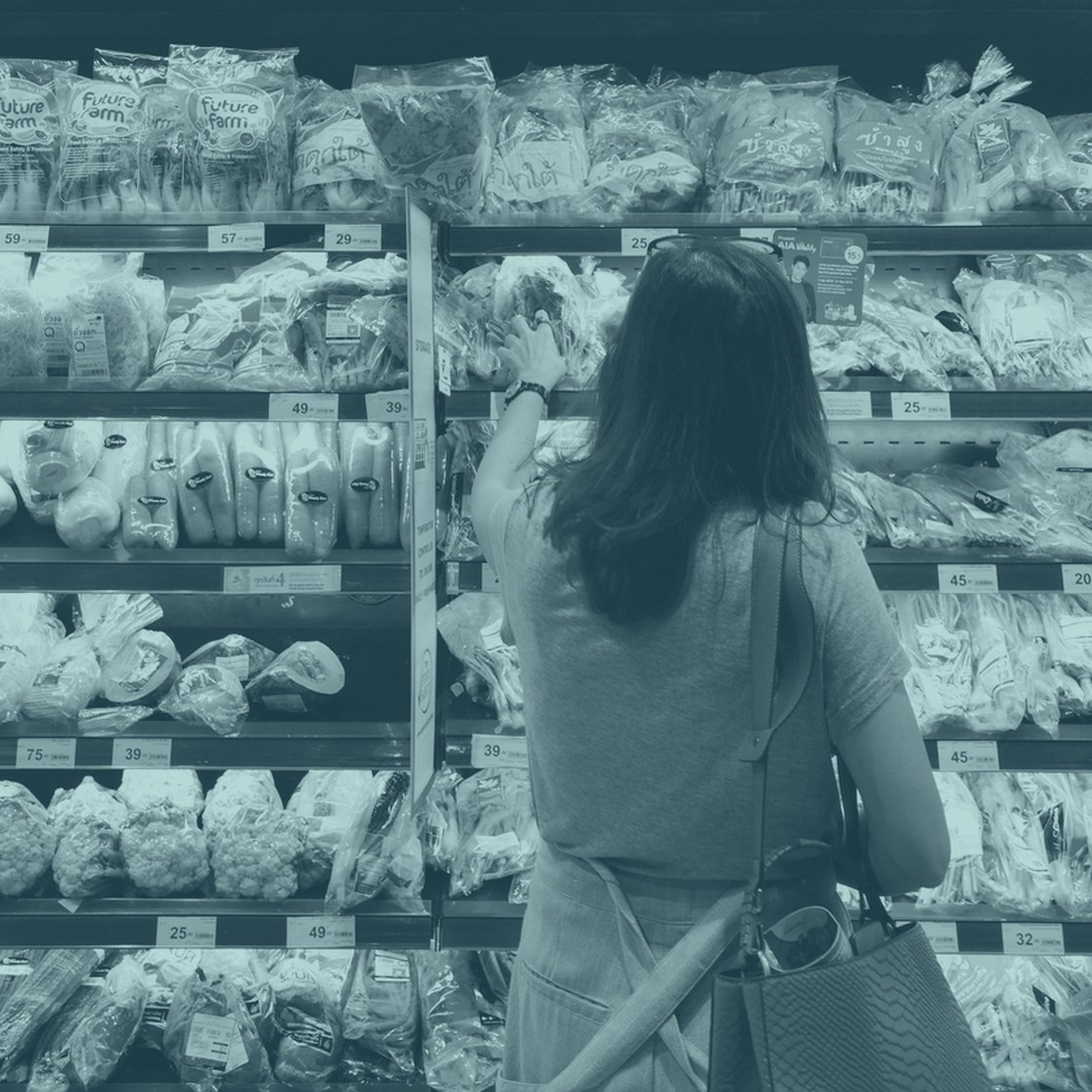 A shopper choosing bread in a supermarket aisle
